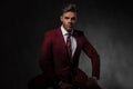 Handsome young man wearing a grena colored suit sitting Royalty Free Stock Photo