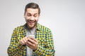 Handsome young man wearing headphones and holding mobile phone while standing against grey wall Royalty Free Stock Photo