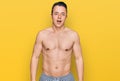 Handsome young man wearing swimwear shirtless afraid and shocked with surprise and amazed expression, fear and excited face Royalty Free Stock Photo