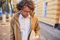 Handsome young man wears spectacles with books outdoors. College male student carrying books in college campus in autumn street Royalty Free Stock Photo