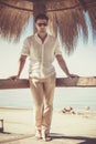 Handsome young man with white shirt and sunglasses relaxed leaning on a wooden bar. Barefoot without shoes. During the summer, Royalty Free Stock Photo