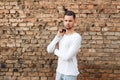 Handsome young man in a white T-shirt posing near a brick wall. Royalty Free Stock Photo