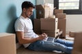 Handsome young man working with computer while taking a break sitting on the floor at home Royalty Free Stock Photo