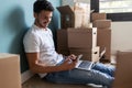 Handsome young man working with computer while using smart phone sitting on the floor at home Royalty Free Stock Photo