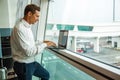 Handsome young man working with laptop in airport when waiting for his plane. Royalty Free Stock Photo