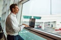 Handsome young man working with laptop in airport when waiting for his plane. Royalty Free Stock Photo