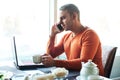 Handsome young man working with notebook, talking on the phone,, while enjoying coffee in cafe Royalty Free Stock Photo