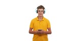 man in yellow t-shirt listening to music with headphones and his smartphone, while standing against white background. Royalty Free Stock Photo