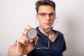 Handsome young medic holding a stethoscope, isolated over white