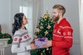 handsome young man giving christmas present to his beautiful girlfriend Royalty Free Stock Photo