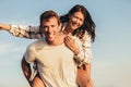 Young man giving piggyback ride to girlfriend on beach. Young couple enjoying summer holidays Royalty Free Stock Photo