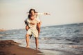 Young man giving piggyback ride to girlfriend on beach. Young couple enjoying summer holidays Royalty Free Stock Photo