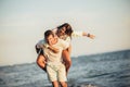 Young man giving piggyback ride to girlfriend on beach. Young couple enjoying summer holidays Royalty Free Stock Photo