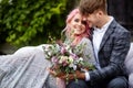 Handsome young man hugs tender woman with pink hair sitting on the white couch