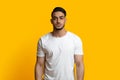 Handsome young middle eastern guy posing on yellow studio background