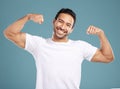 Handsome young mixed race man flexing his biceps while standing in studio isolated against a blue background. Athletic Royalty Free Stock Photo
