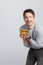 Handsome young modern crazy smiling man holding a big vegan burger a sandwich in your hands and looking at the camera. Royalty Free Stock Photo