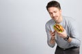 Handsome young modern man holding and looking at a big vegan burger a sandwich in your hands on gray background. Royalty Free Stock Photo