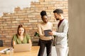 Young multiethnic business couple with digital tablet standing and discussing in the modern office Royalty Free Stock Photo