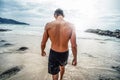 Handsome young muscular italian man posing shirtless on the beach, summer time. Back view Royalty Free Stock Photo