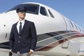 Handsome young pilot standing by private airplane Royalty Free Stock Photo