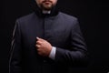 Handsome young priest with bread posing on a black background.