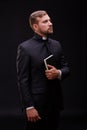 Handsome young priest with bread posing on a black background.