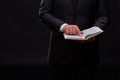 Handsome young priest with bread posing on a black background.