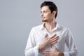 Handsome young proud man in shirt holding hand on chest on grey Royalty Free Stock Photo