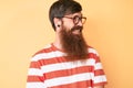 Handsome young red head man with long beard wearing casual clothes and glasses looking to side, relax profile pose with natural Royalty Free Stock Photo