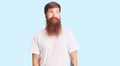Handsome young red head man with long beard wearing casual white tshirt smiling looking to the side and staring away thinking Royalty Free Stock Photo
