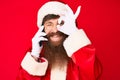 Handsome young red head man with long beard wearing santa claus costume talking on the phone smiling happy doing ok sign with hand Royalty Free Stock Photo