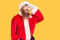 Handsome young red head man with long beard wearing santa claus costume very happy and smiling looking far away with hand over Royalty Free Stock Photo