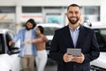 Handsome young salesman with digital tablet in luxury dealership salon Royalty Free Stock Photo