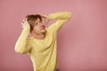 Handsome young scary sad angry man in yellow sweater looking up on copy space over pink background. Concept of migraine sick head