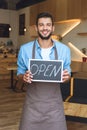 handsome young small business owner holding open sign and smiling Royalty Free Stock Photo