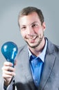 Handsome young smart man holding a blue light bulb Royalty Free Stock Photo