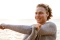 Handsome young sports man standing on the beach listening music with earphones make stretching exercises. Royalty Free Stock Photo