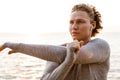 Handsome young sports man standing on the beach listening music with earphones make stretching exercises. Royalty Free Stock Photo