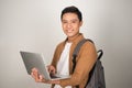 A handsome young student using laptop and carrying backpack isolated on white background Royalty Free Stock Photo