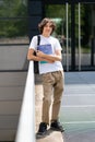 Handsome young student wearing backpack standing outdoors on university enjoying sunlight embracing Royalty Free Stock Photo