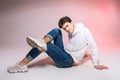 Handsome young stylish man sitting on the floor in studio. Teenager model posing while sitting on a pink background in casual Royalty Free Stock Photo