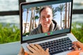 handsome and young successful indian man freelancing surfing remote work with a laptop on the beach by the ocean.india