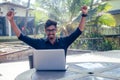 Handsome and young successful indian man freelancing surfing remote work with a laptop on the beach by the ocean.india