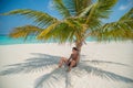 Handsome young tanned man resting under palm tree at the beach at the tropical island luxury resort