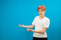 Handsome young teen boy points hands aside isolated on blue. Friendly well-looking boy paying your attention at copy space, best Royalty Free Stock Photo