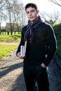 Handsome young teenage male student walking to school in sunshine, carrying books and rucksack Royalty Free Stock Photo