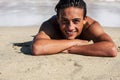 Handsome young teenager boy smile lay down on the sand at the beach with shore sea in background - student enjoying summer holiday Royalty Free Stock Photo