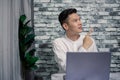 Handsome young thinking while serious working at home with laptop on desk