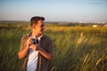 Handsome young traveler man with vintage camera,on a green meadow background. Travel mood. Photography. Royalty Free Stock Photo